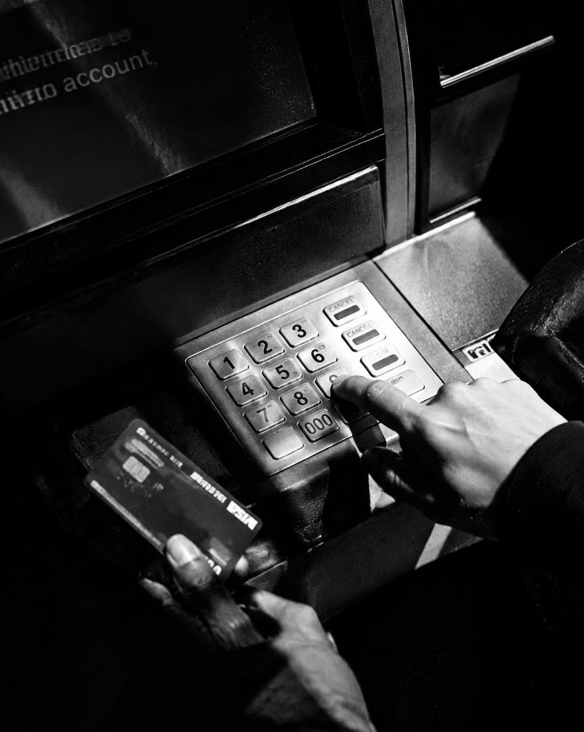 A hand entering a PIN at an ATM keypad