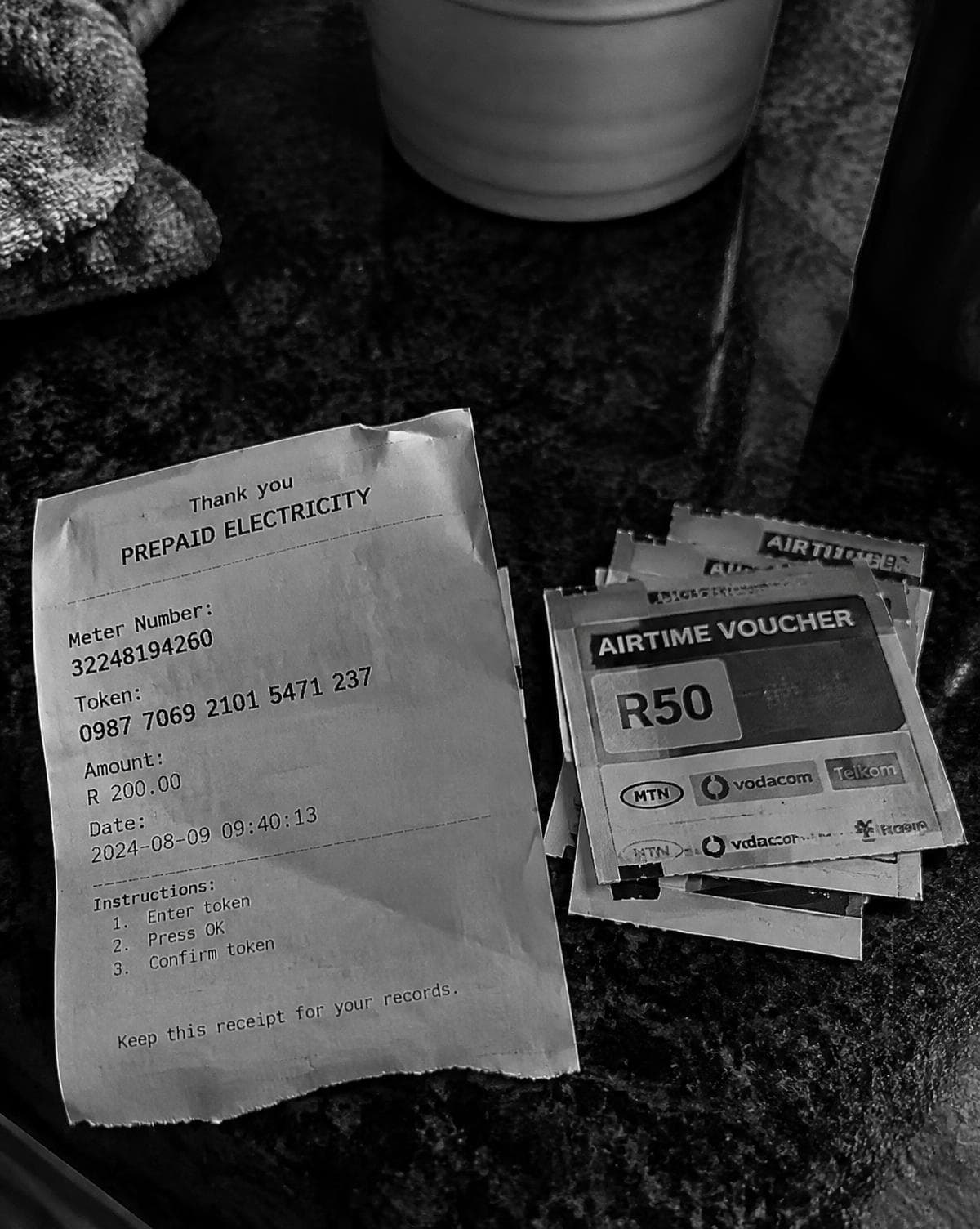 A prepaid electricity slip and airtime vouchers on a counter
